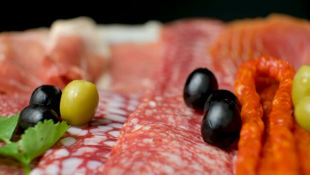Meat platter - sausages, salami and other types of meat delicacies with olives and herbs