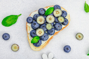 Fresh bread sandwiches with sweet blueberries, cream cheese and basil leaves. Good morning concept