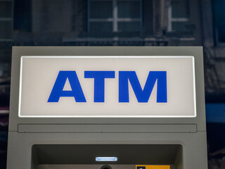 Silver automatic teller machine hanging on a gray concrete wall