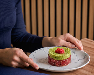 Woman eating tuna tartare and avocado in a restaurant. Mediterranean lifestyle diet concept. Healthy lunch or dinner.