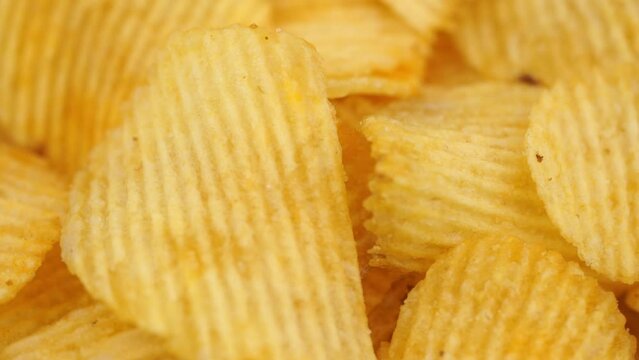 Crispy potato chips rotating in macro. Golden fried potatoes close up. Potato snack for unhealthy fast food. 
