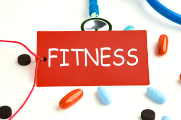 Fitness, healthy lifestyle and sport concept: FITNESS written on a red card on a stethoscope with...