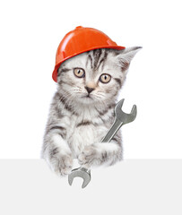 Cute kitten wearing hardhat holding the wrench and looking above blank white banner. Isolated on white background