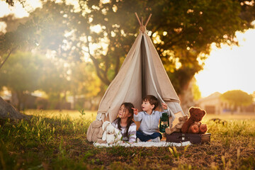 Teepee, kids and fun in garden tent outdoor in nature for camping, playing and adventure with pointing. Cloth, light and fantasy house for children in forest with imagination, suitcase and teddy bear © peopleimages.com