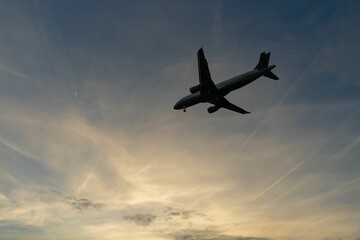 an airplane flying in the air on a cloudy day with sunset