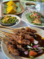 Lamb, mutton grilled skewer satay served with soy sauce sauce with sliced shallots, tomatoes, cucumber and cayenne pepper