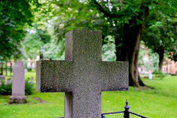 Cross in the center of a grassy cemetery, surrounded by trees