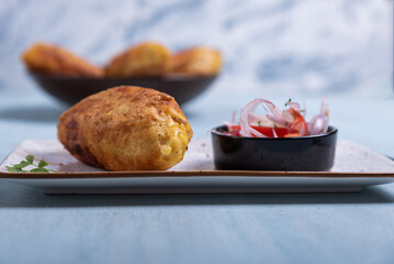 Traditional Peruvian dish: tasty stuffed potatoes served with onion and tomato salad.