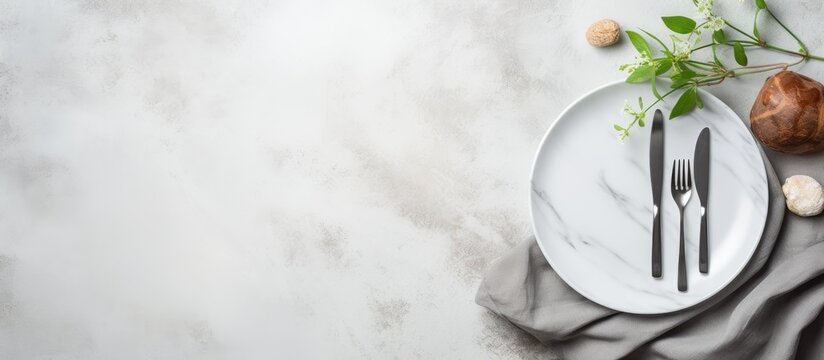 A minimalistic copy space image featuring an unoccupied white plate accompanied by silver cutlery neatly arranged on a gray stone table alongside a folded napkin This food themed backdrop is ideal fo