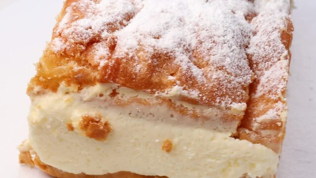Polish traditional Carpathian cake, rotation in circle. a piece of cake, Turning. Cake made of choux pastry dough and custard cream, topped with powdered sugar.