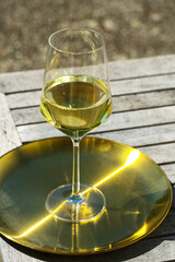 glas of white wine on golden tablet, in the garden