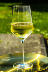 glas of white wine on golden tablet, in the garden