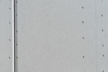 Smooth pale grey surface of a building wall with several holes