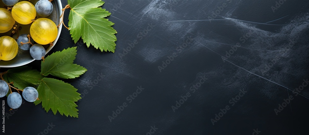Poster some organic gooseberries from the garden and a leaf on a blue gray plate and a dark slate backgroun