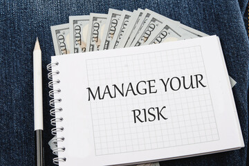 Business and manage your risk concept. Concept word Manage your risk on a notebook lying on jeans with dollar bills