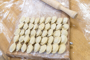 Raw dumplings were laid out on a wooden board for cooking. Next to it is a rolling pin for rolling...