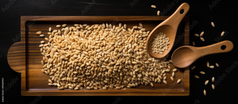 Poster wheat seeds in a wooden plate and wooden scoop over a black background with copy space viewed top do