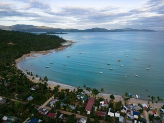 Obraz premium an aerial view of a beach resort in the distance and water surrounding: Port Barton, Philippines