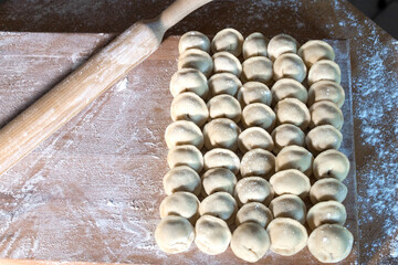 Raw dumplings were laid out on a wooden board for cooking. Next to it is a rolling pin for rolling...