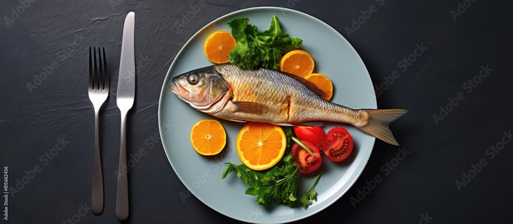 Poster Leafy salad with red fried fish and orange on a white plate with a fork on a grey background Background image copy space