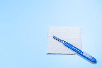 A blue surgical blade is on a white paper towel. Concept of cleanliness and sterility, as the...