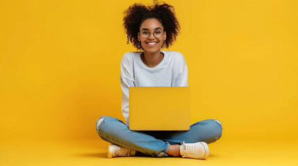 Smiling attractive young woman sitting on the floor with her legs crossed holding a laptop computer