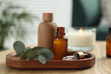 Aromatherapy. Bottles of essential oil and eucalyptus leaves on wooden table