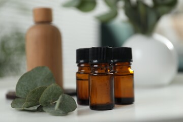 Aromatherapy. Bottles of essential oil and eucalyptus leaves on white table