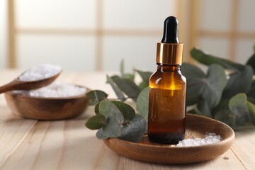 Aromatherapy. Bottle of essential oil, sea salt and eucalyptus leaves on wooden table