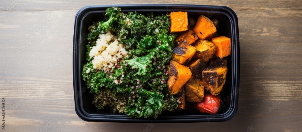 Poster an overhead view of a lunch box bowl containing sauteed kale quinoa and roasted sweet potato with sp