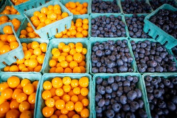 High angle shot of boxes of kumquats and blueberries at a market