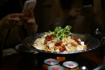Woman at a table enjoying a meal while capturing the moment with her mobile phone
