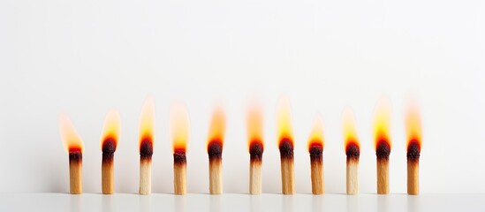 Fototapeta premium A copy space image of a row of three matches one of which is lit burning on a white background