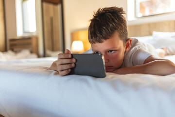 Little boy playing online games on mobile phone.