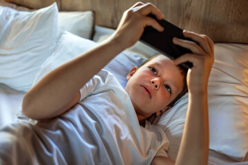 Little boy playing online games on mobile phone.