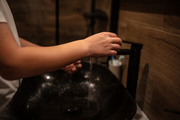 An unknown child washing their hands in a bathroom at home. Unrecognizable Caucasian boy with...
