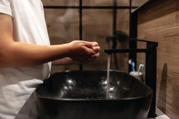Closeup of kid rinsing soap in bathroom basin for disinfection, care or cleanliness at house. Child, tap and washing hands in water for hygiene, cleaning or bacteria or germ removal in sink at home.