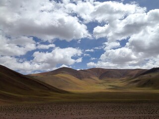 an out side road in a wide open field under fluffy clouds