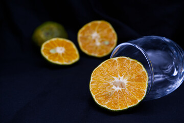 Half-orange with wine glass placed on black background. Orange texture with dark theme for...