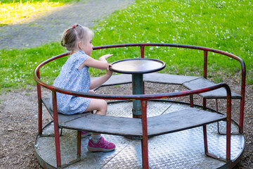 happy preschool girl, child spinning on carousel on summer day, dizziness and balance, joyful...