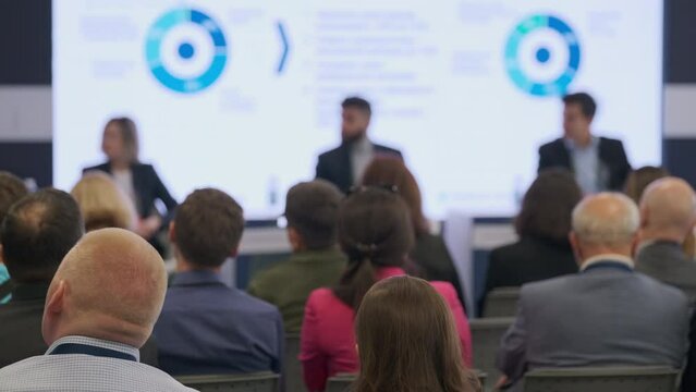 A focused view of a business presentation in a modern conference room, showcasing audience engagement with blurry foreground.