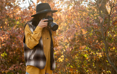 woman, with attention to detail and the beauty of nature, takes photographs in the autumn forest to...