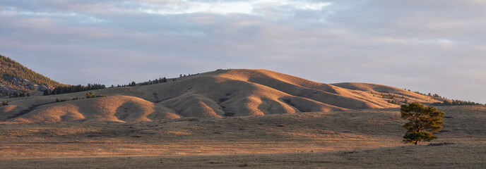 Sunrise on an empty valley amazing hilly landscape. Colorful grassy and hilly natural landscape in...