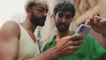 Homosexual couple uses map application on mobile phone while standing on street of old city