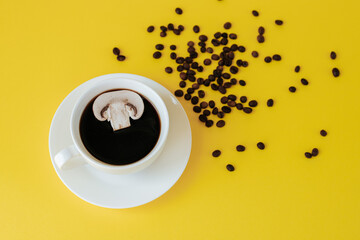 A slice of champignon mushroom floats in a cup of coffee. a cup and saucer stand on a yellow...