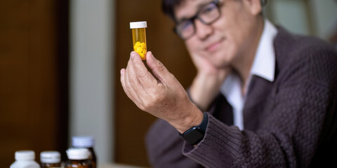 Senior asian man examining prescription medication at home