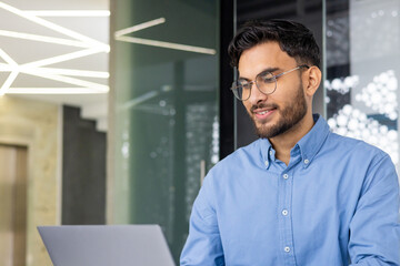 Young businessman working confidently on laptop in modern office environment