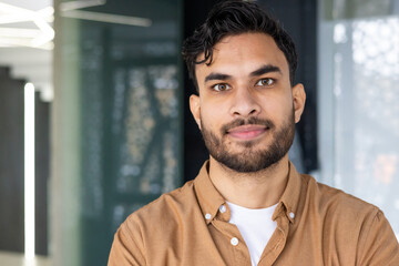 Obraz premium Confident young man with beard smiling in a modern office environment