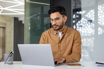 Focused professional working on a laptop in a modern office environment