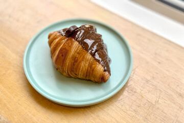 Chocolate Croissant on Light Blue Plate on Wooden Table